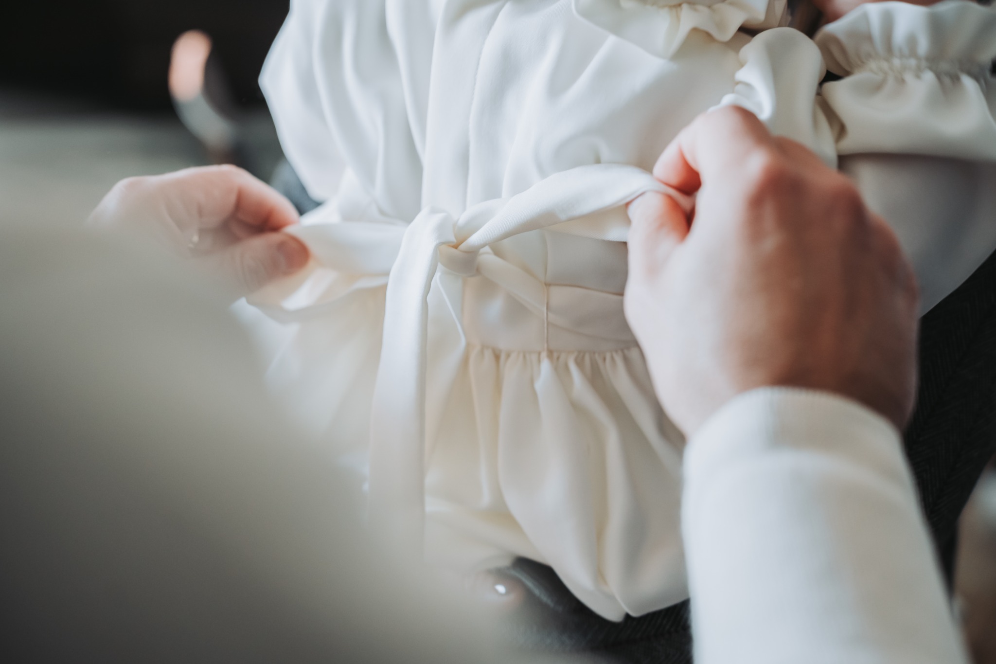 Le mani sistemano l’abito della bambina