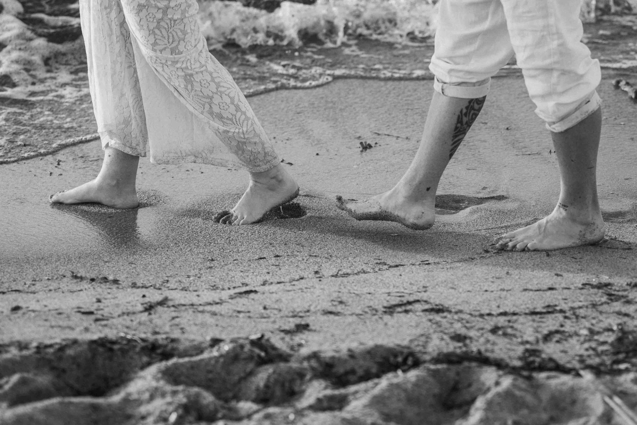La coppia cammina a piedi nudi sulla sabbia in bianco e nero